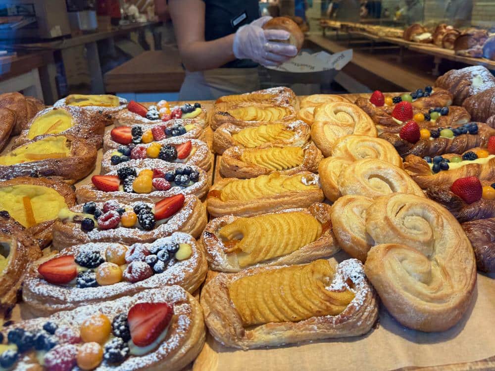 Sweet pastries with fruit and powdered sugar line a bakery window in Miami Beach